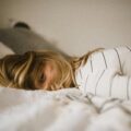 Tired woman lying in bed unable to feel rested despite sleeping