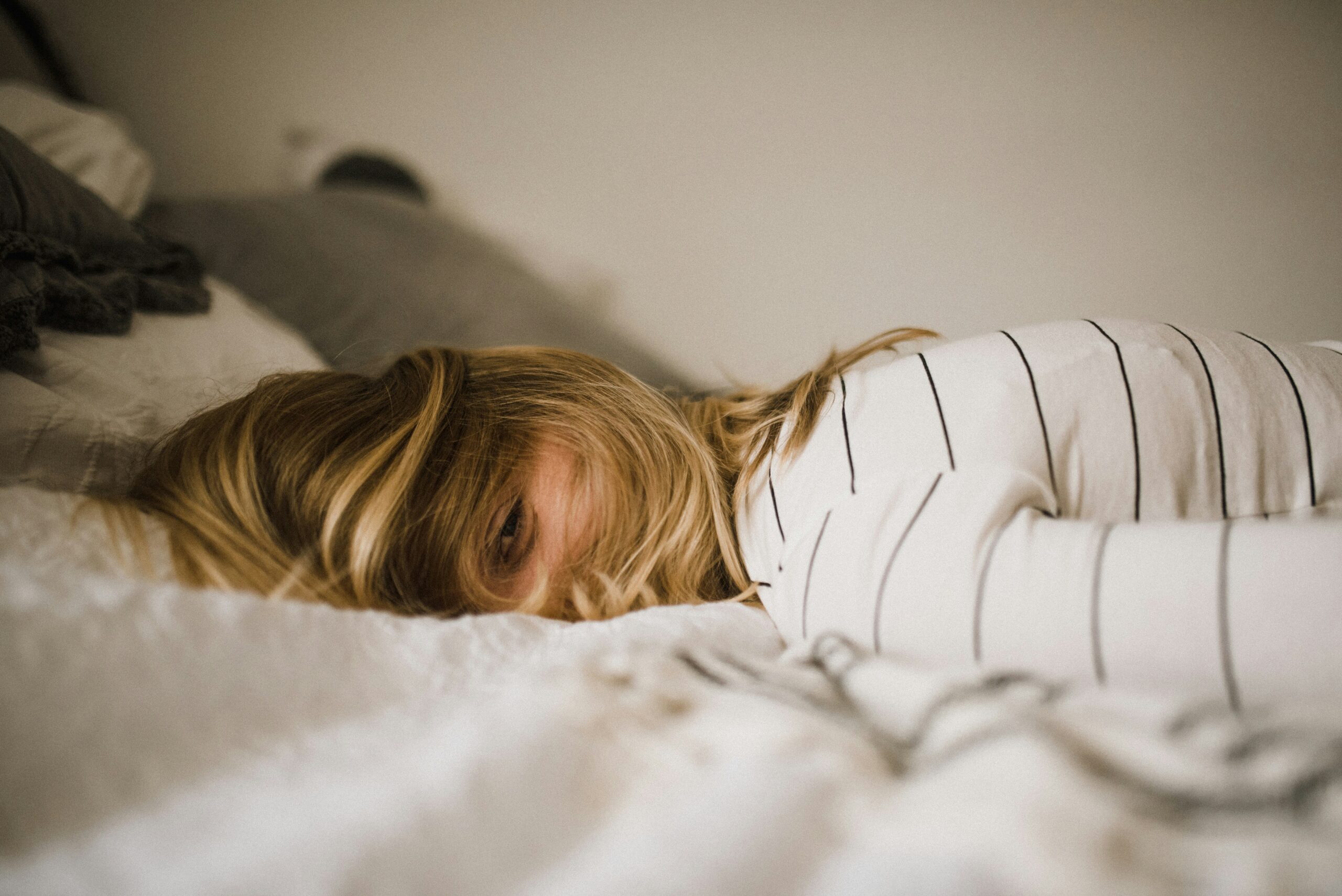 Tired woman lying in bed unable to feel rested despite sleeping